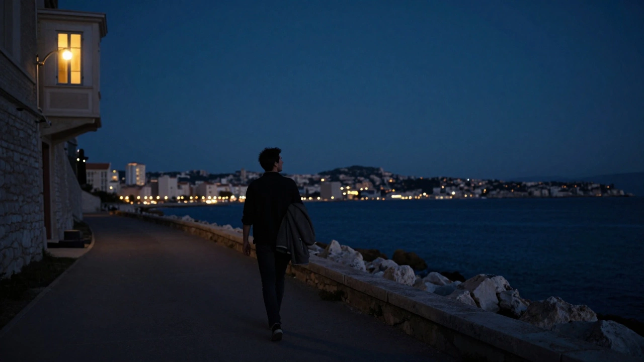 A solitary traveler walks a coastal path at night, looking back at a lit apartment window in Marseille.