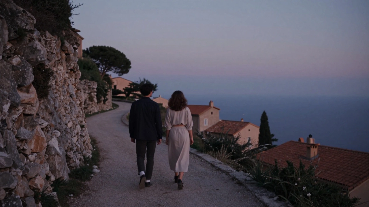 Two individuals stroll a cliffside path near Èze, overlooking the Mediterranean at twilight, sharing peaceful silence.